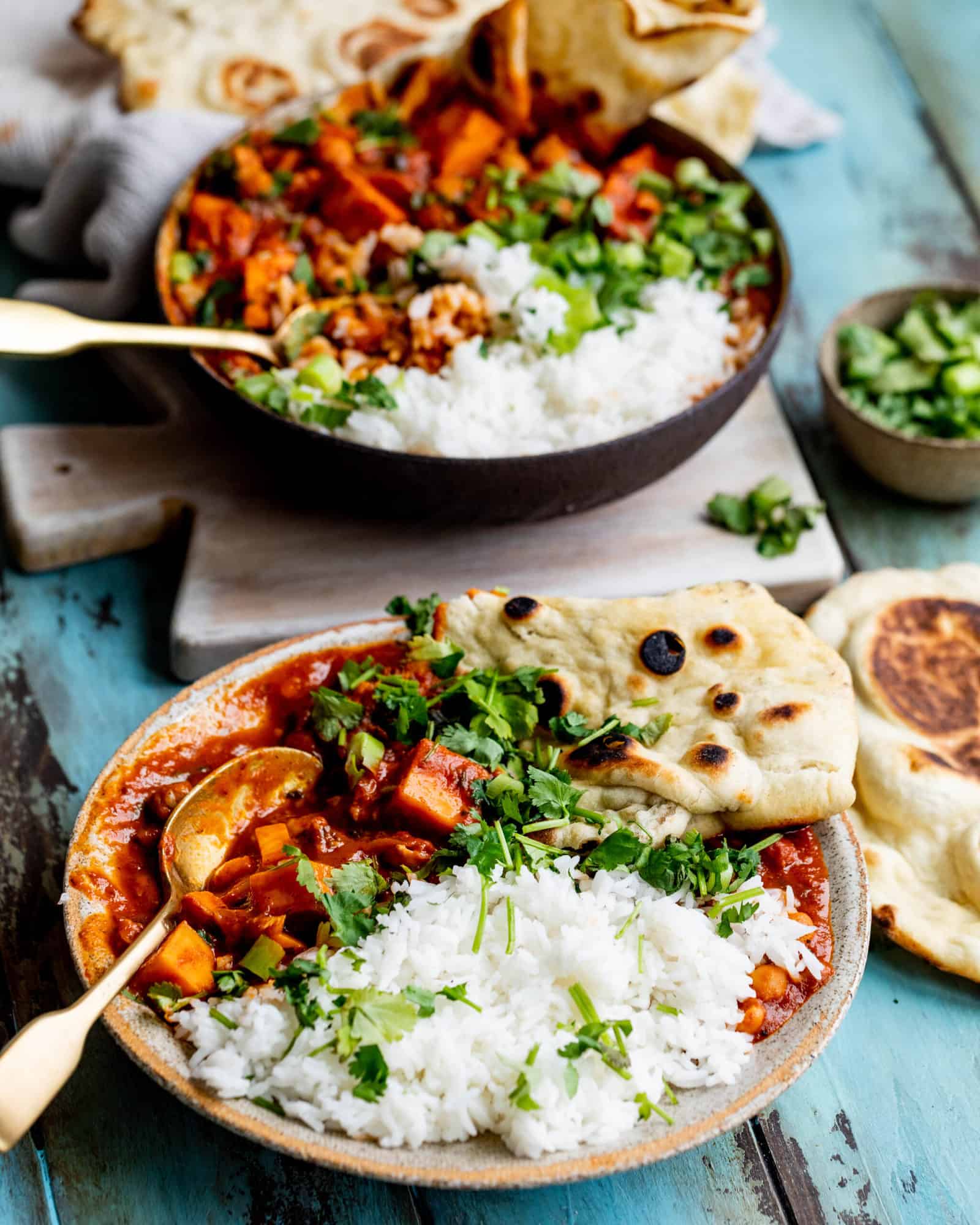 two bowls of curry with rice and naan