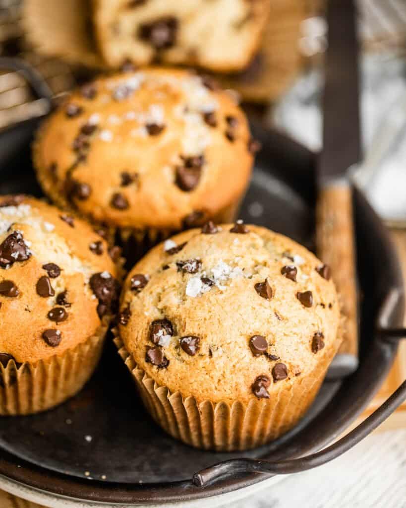 bakery style chocolate chip muffins with a butter knife on a serving tray
