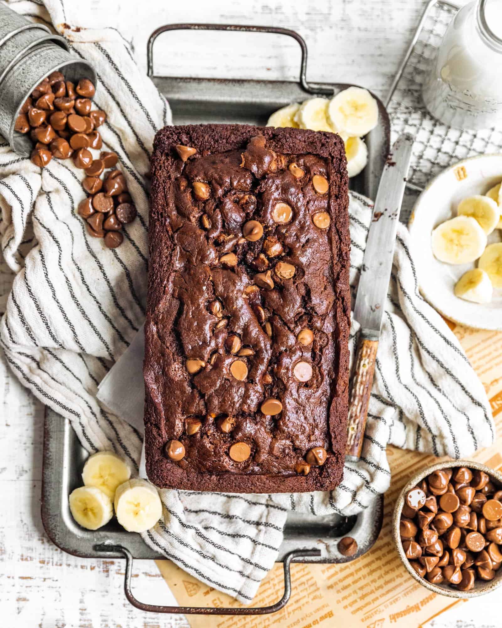 chocolate banana bread on a serving tray with sliced bananas