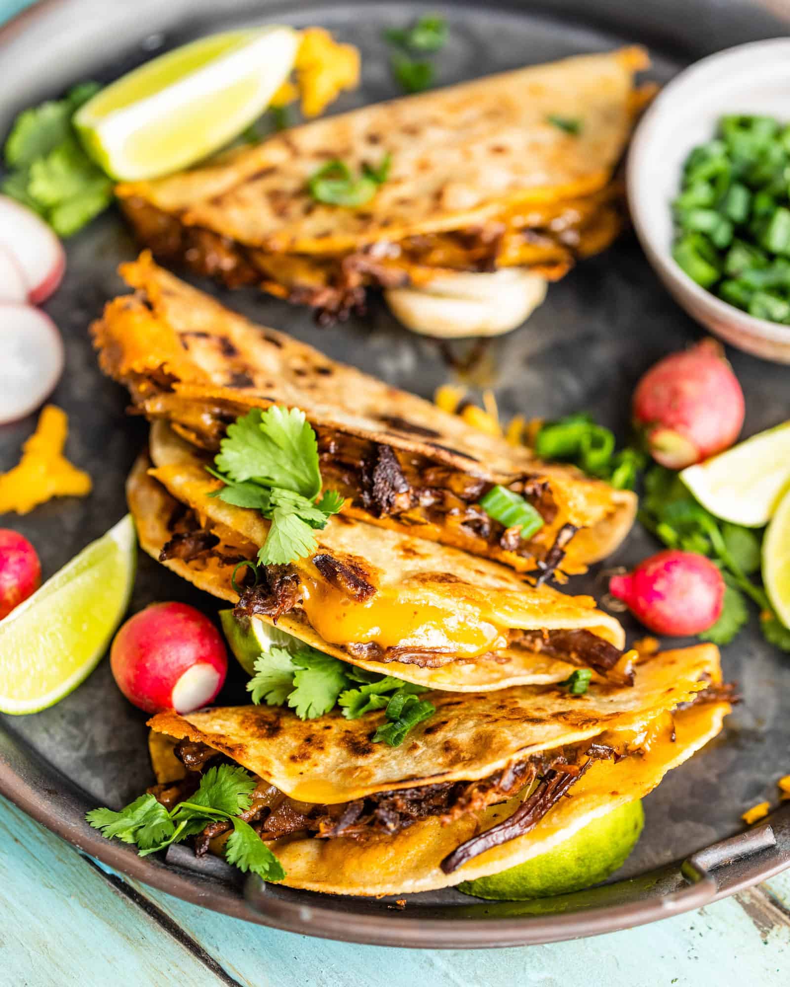crispy chipotle shredded beef tacos on a tray with cilantro and radishes