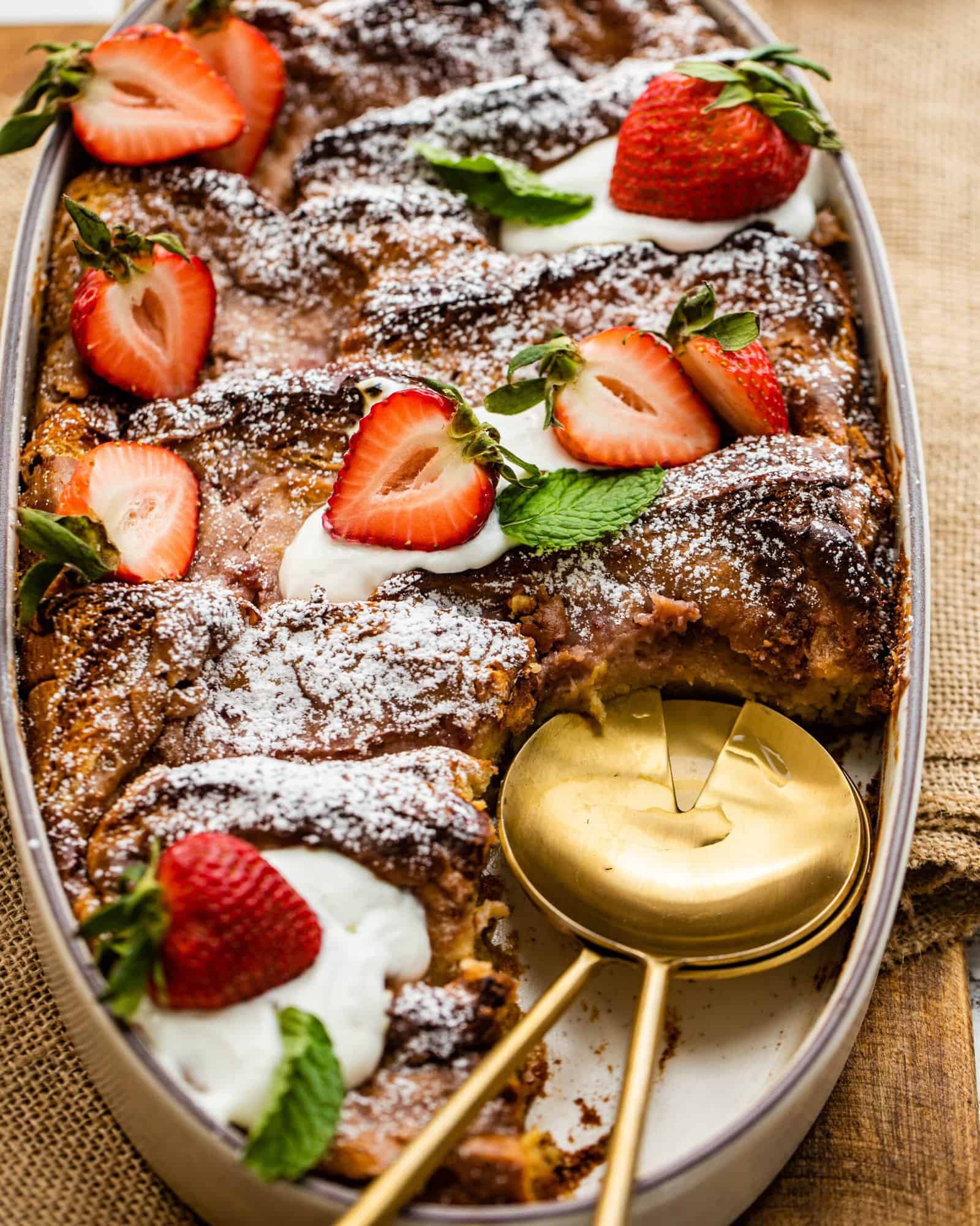 baked strawberry french toast in a serving dish with a serving spoon