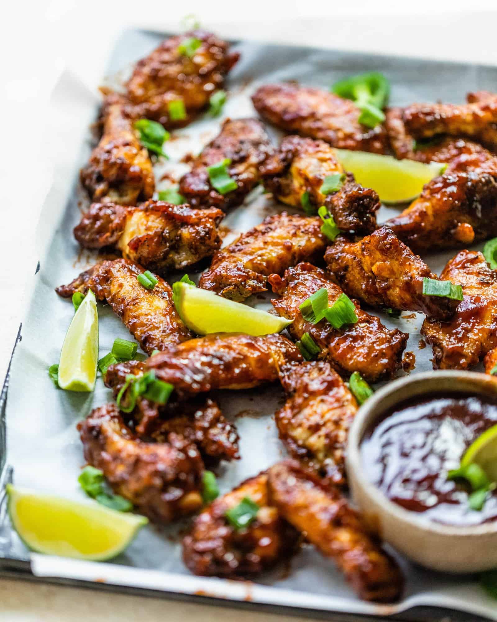 wings on a platter with bbq sauce and limes