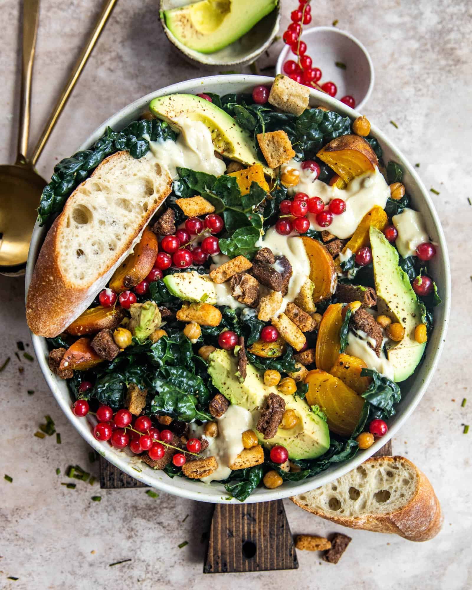 vegan kale caesar salad in a bowl with avocados and red currants