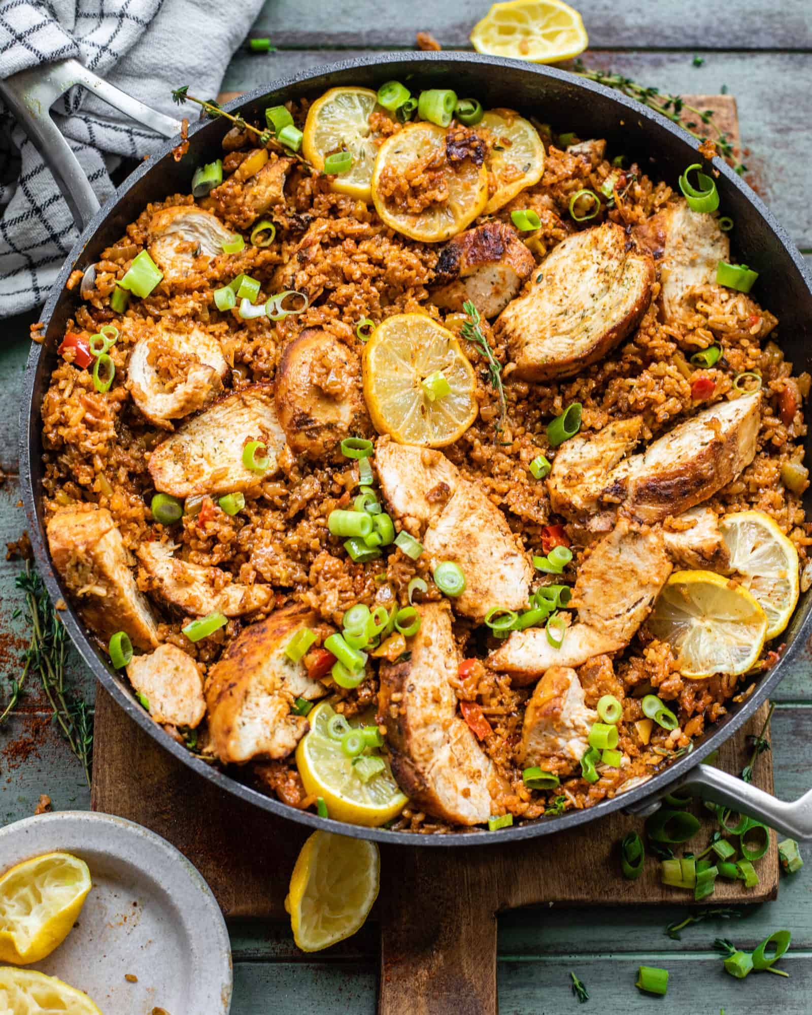 cajun chicken and rice in a skillet with lemons and fresh herbs