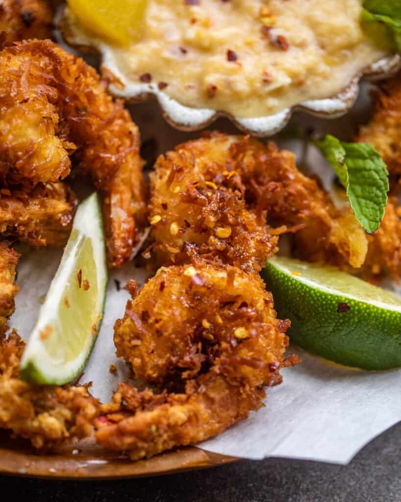 fried coconut shrimp with sliced lime on a plate with sweet dipping sauce