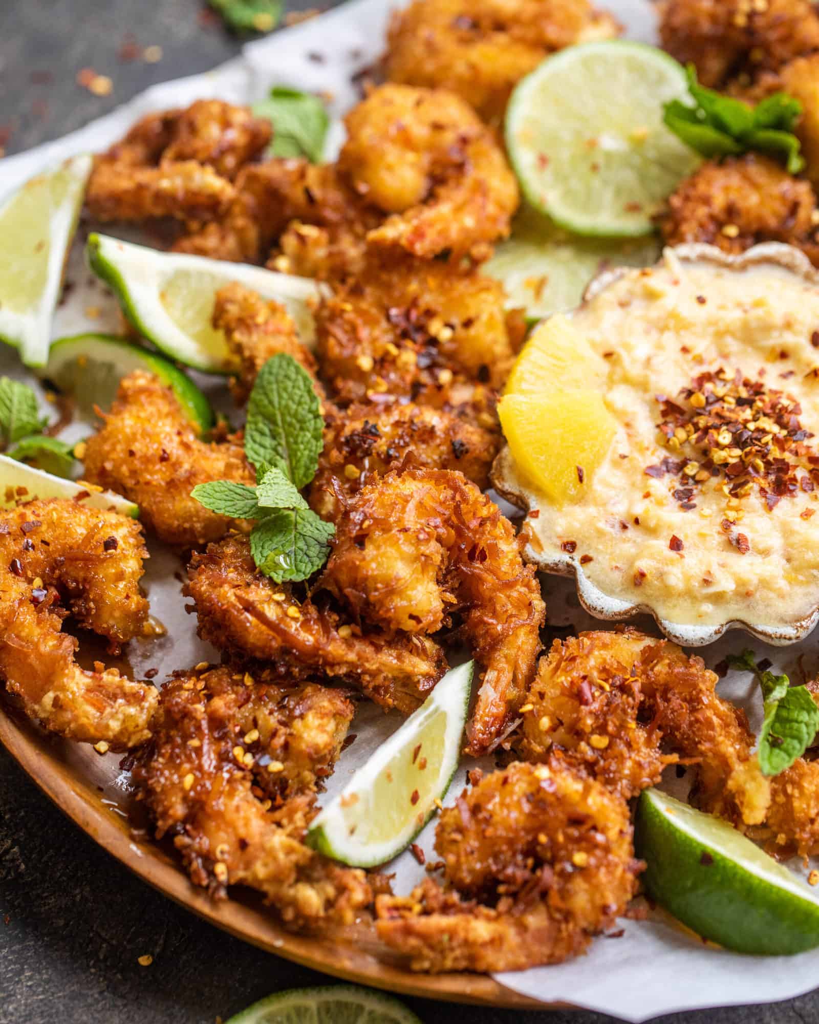 crispy golden fried shrimp on a wooden plate with fresh mint and sliced limes