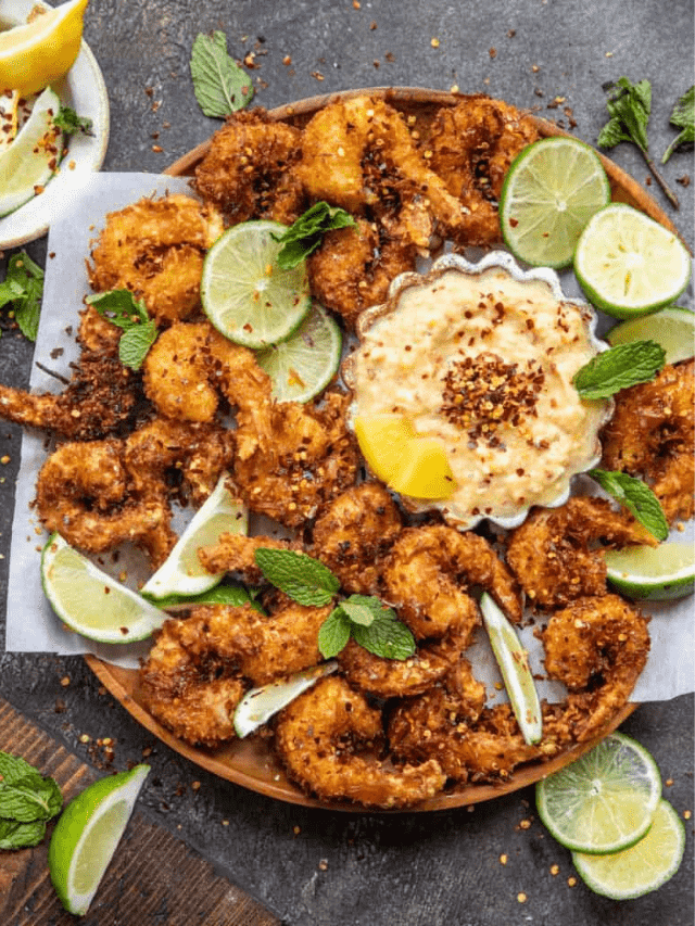 fried shrimp on a serving tray with limes and dipping sauce