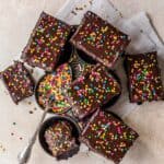 confections on a baking pan with a spoon full of sprinkles