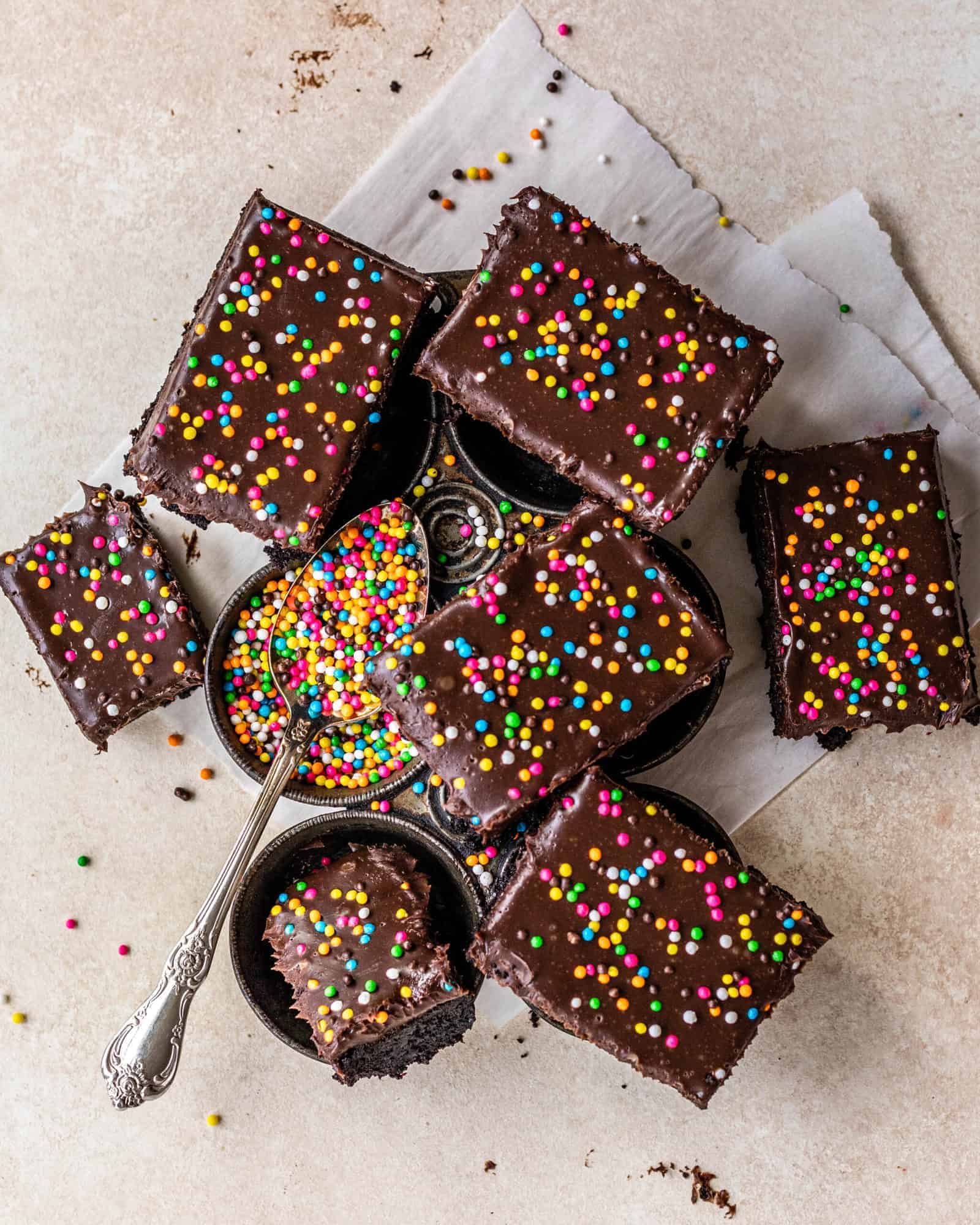 confections on a baking pan with a spoon full of sprinkles