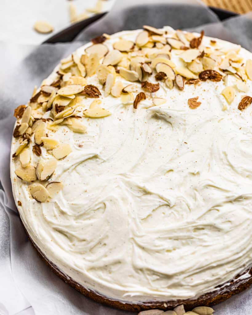 a finished almond cake with mascarpone frosting with almonds on top