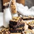 walnut brownies stacked on top of each other next to a bottle of milk