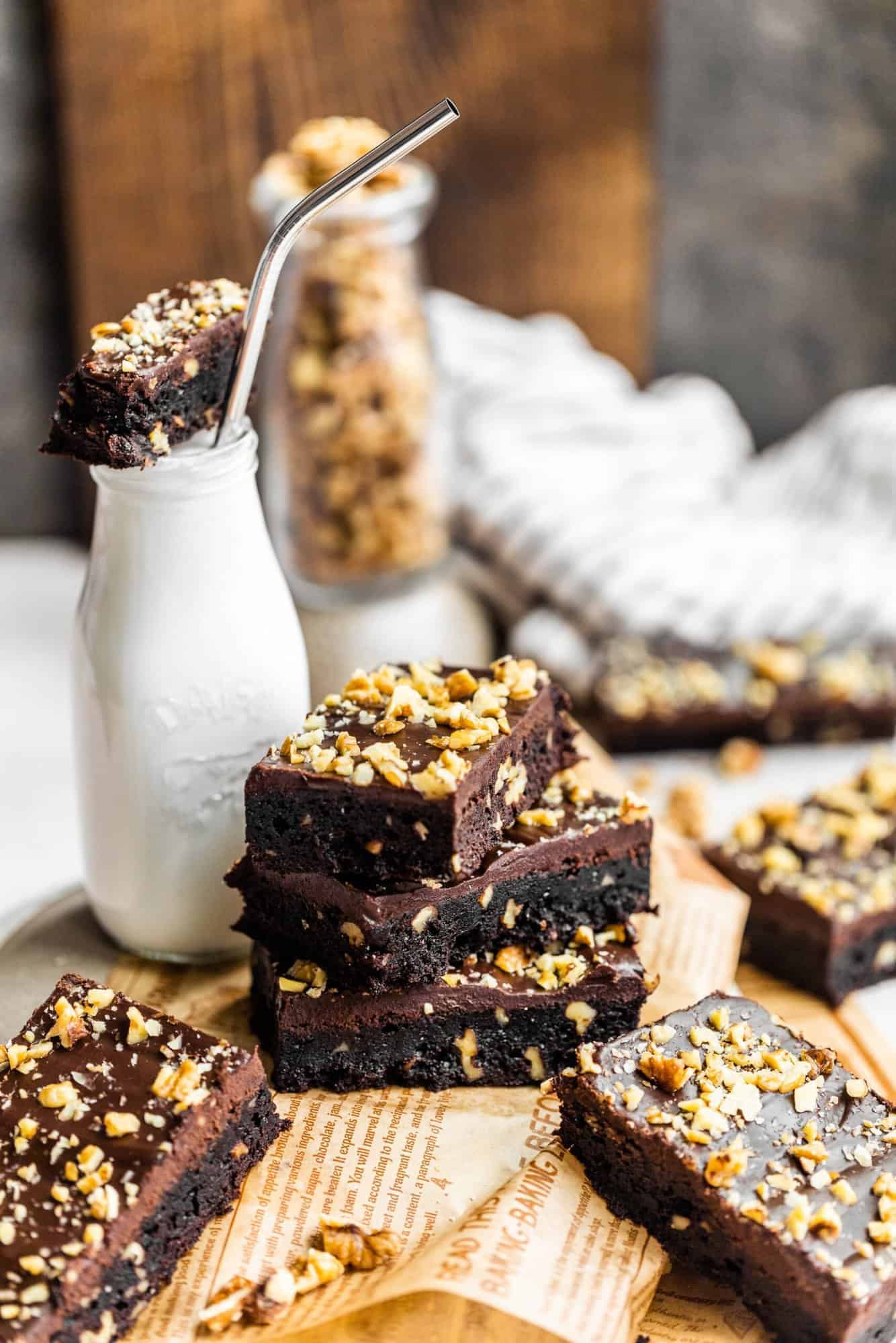 walnut brownies stacked on top of each other next to a bottle of milk