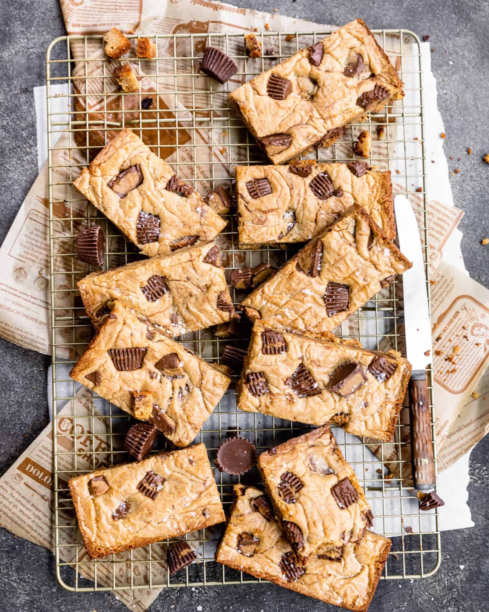 peanut butter cup blondies on a cooling rack with a butter knife