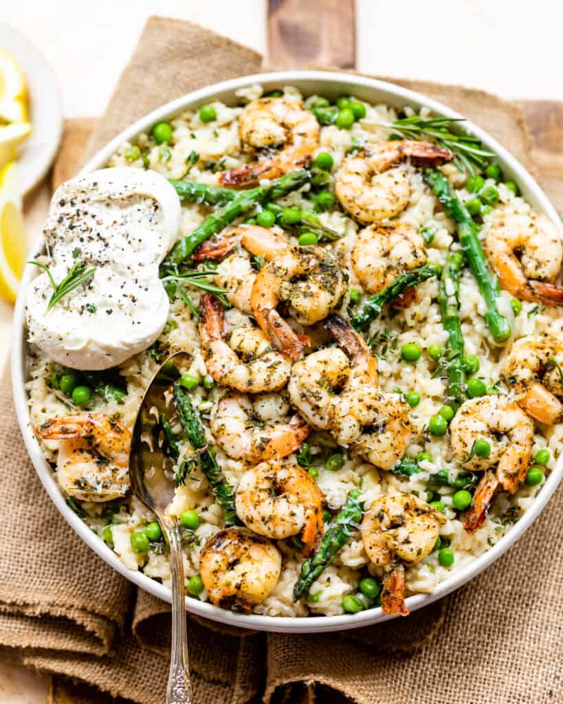 Spring Risotto topped with garlic butter shrimp in a large serving bowl