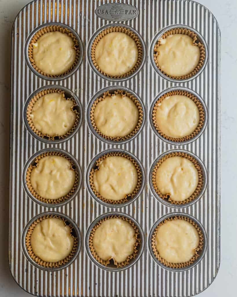 a cupcake pan lined with cupcake liners and filled with lemon raspberry cupcake batter