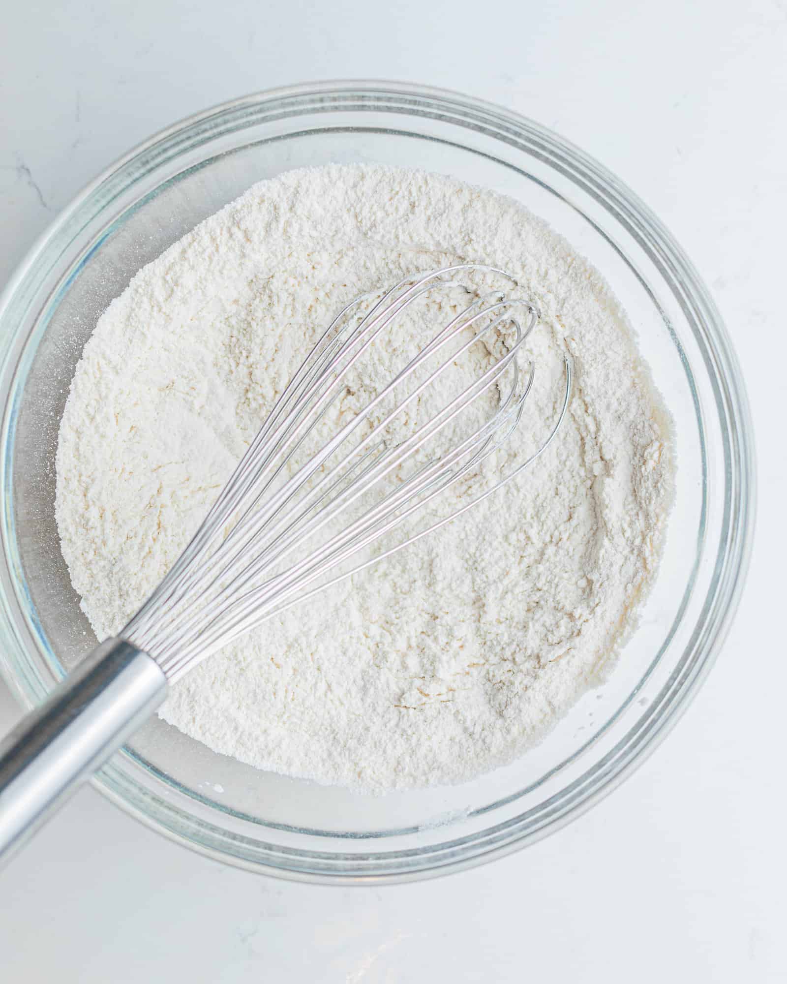 flour, baking powder, baking soda, and salt mixed together in a mixing bowl to form the dry ingredients for this cupcake recipe