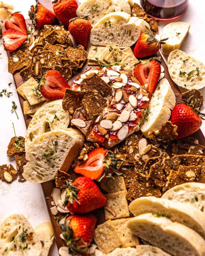brie, fresh strawberries, crackers, and bread on a serving board