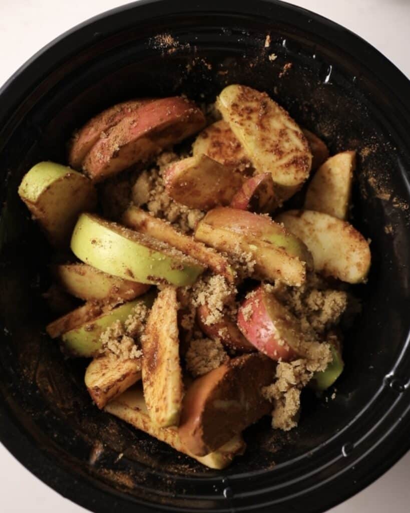 fruit in a slow cooker tossed in brown sugar and spices