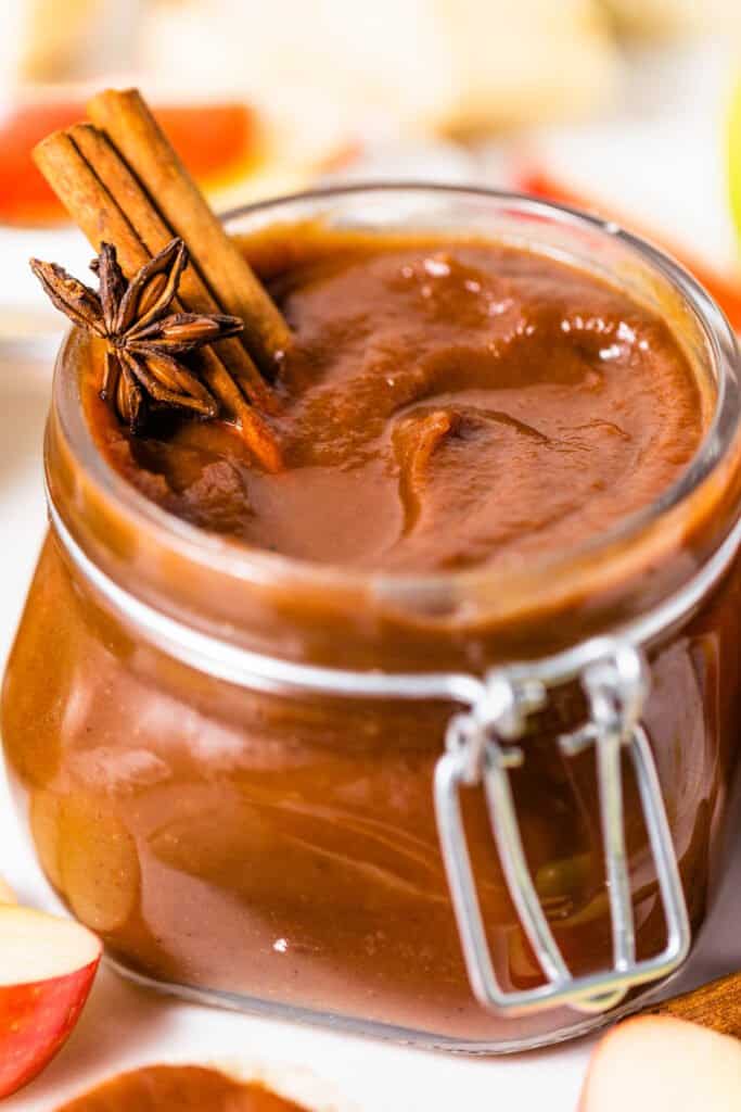 slow cooker apple butter in a jar with cinnamon sticks and star anise