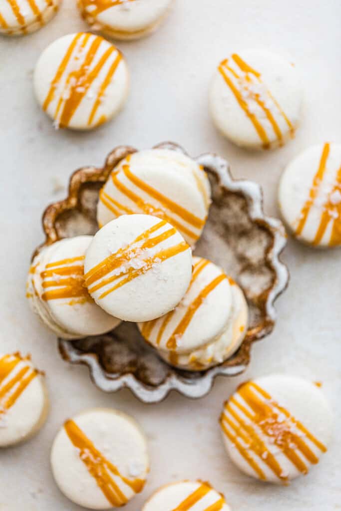 salted caramel macarons in a bowl on a white surface