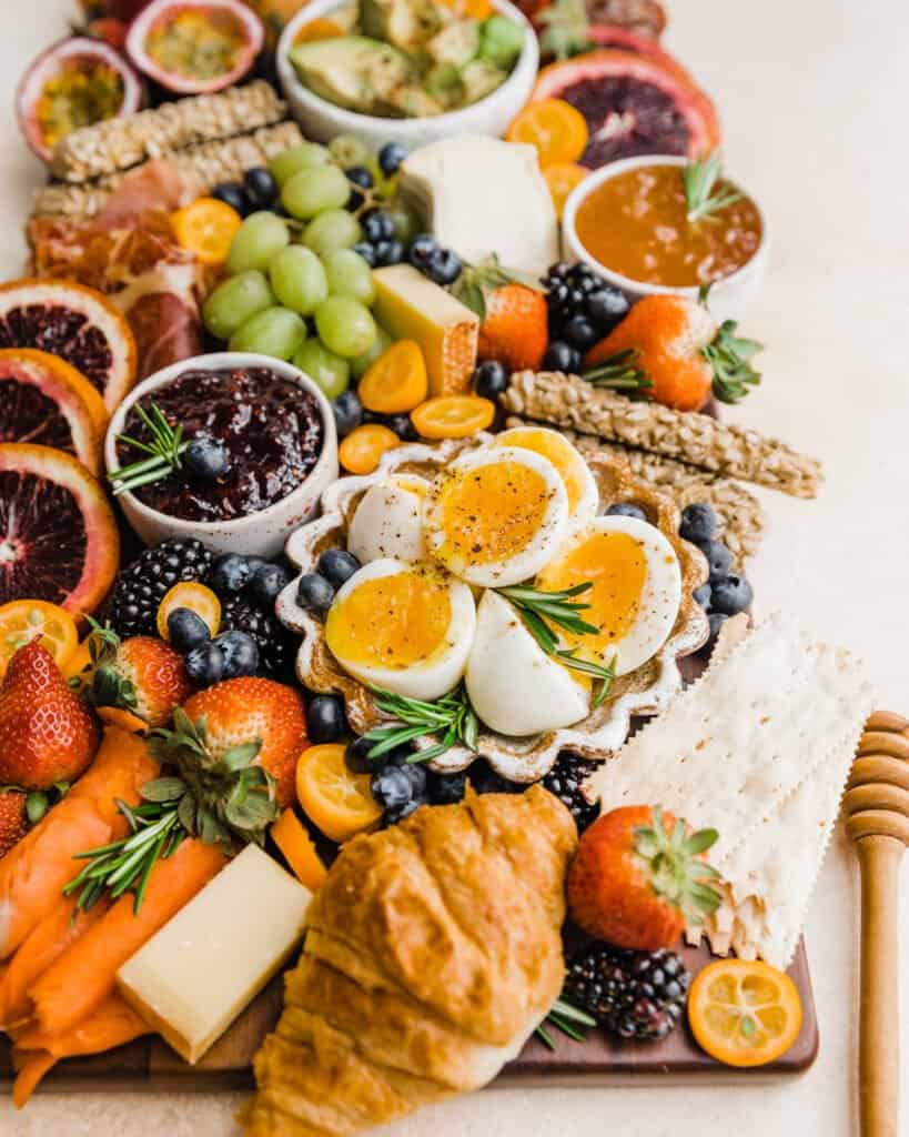 fresh fruits, soft cheeses, fresh berries and grapes on a wooden serving tray