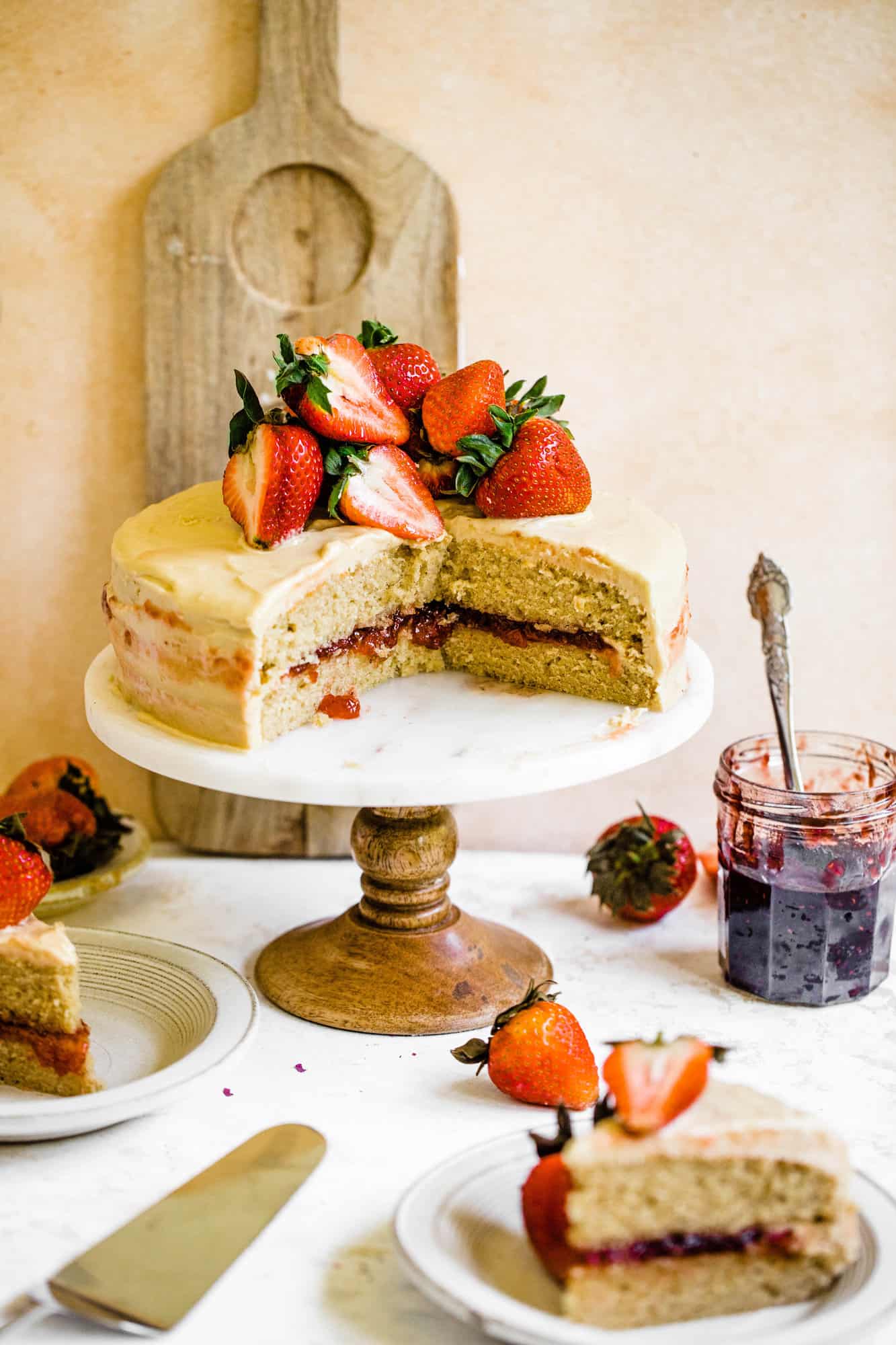 strawberry jam cake on a cake stand with cake slices on a plate