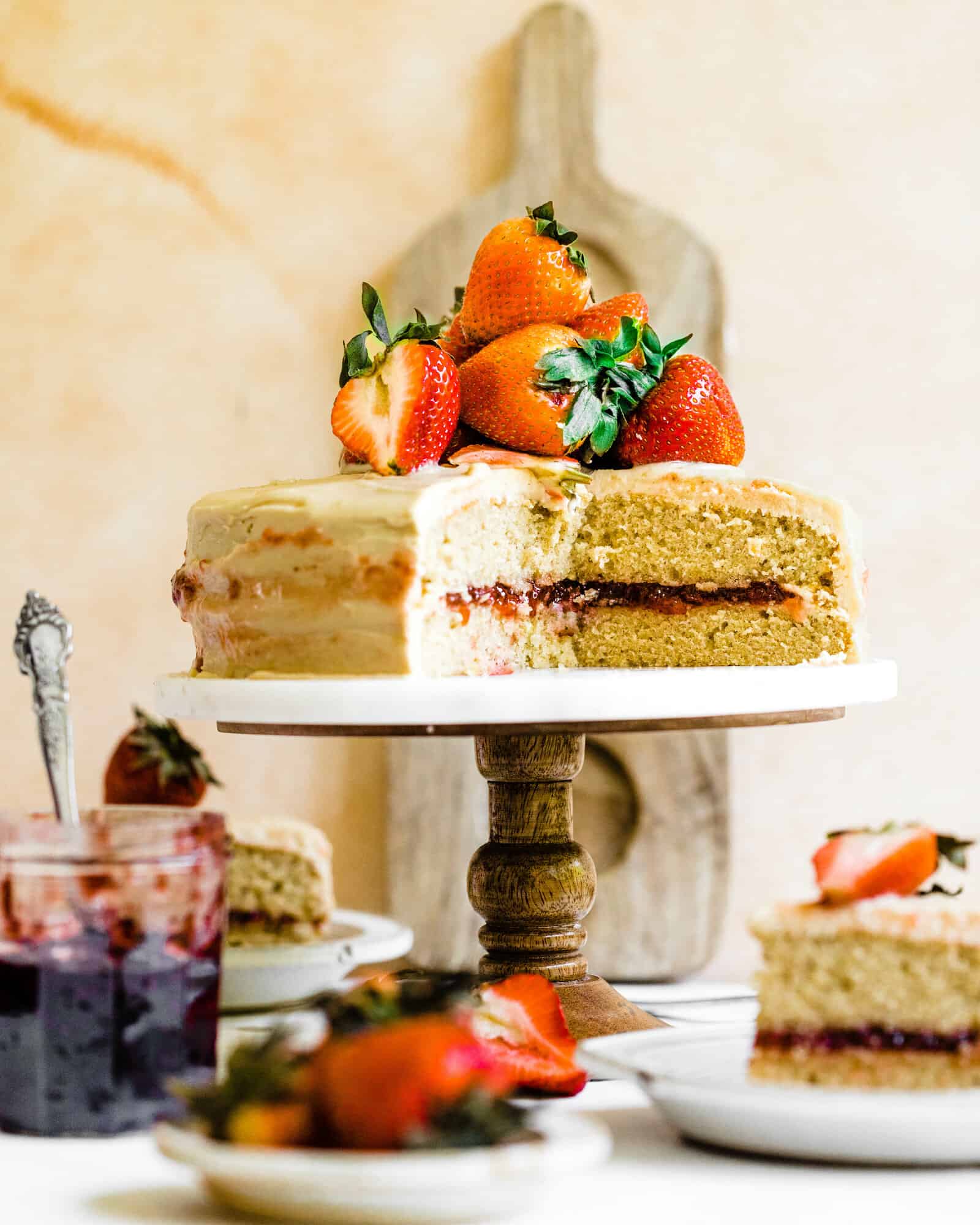 Jam Cake on a cake stand topped with strawberries