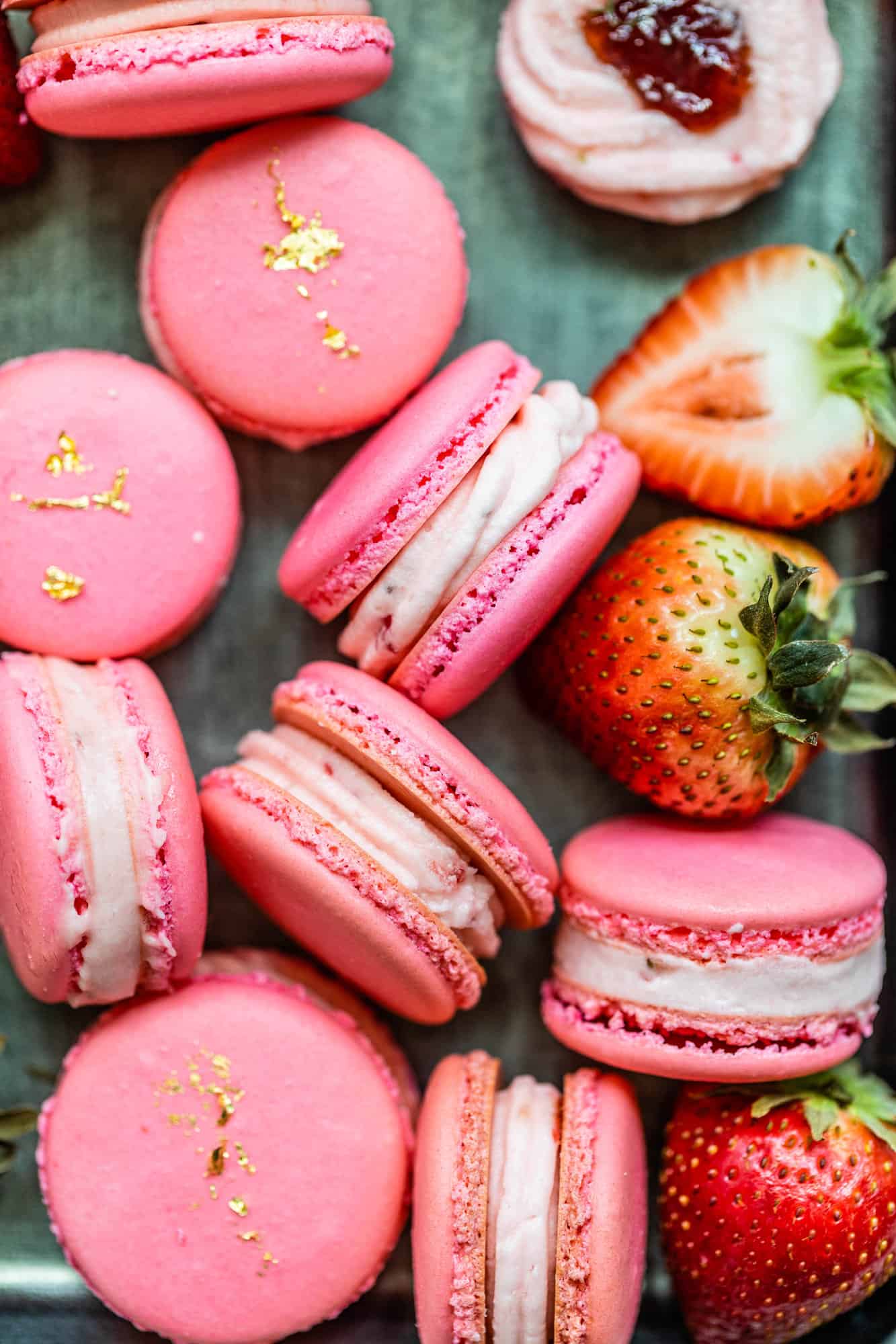 strawberry macarons on a plate with fresh strawberries