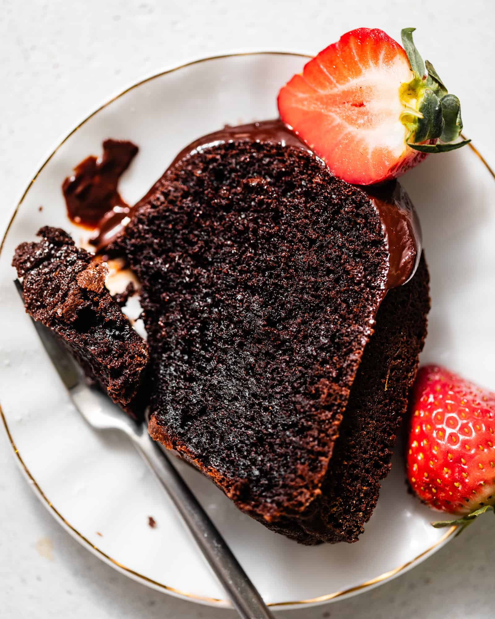 a slice of chocolate pound cake on a plate with a strawberry and a fork