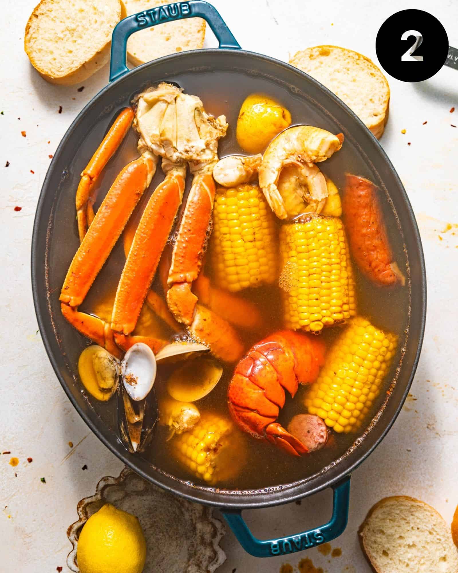 a pot full of broth with ingredients to make the cajun seafood boil