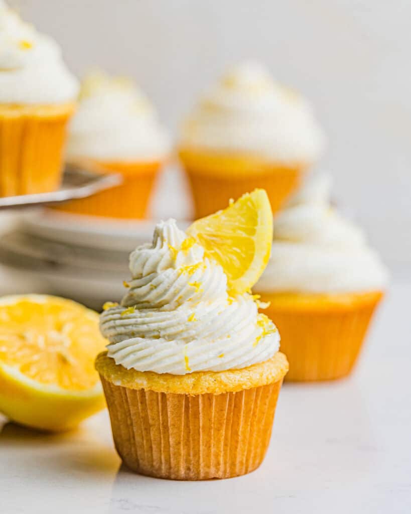 lemon drizzle cupcakes on a table with sliced lemons