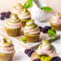 matcha cupcakes on a table with a tea cup and berries.