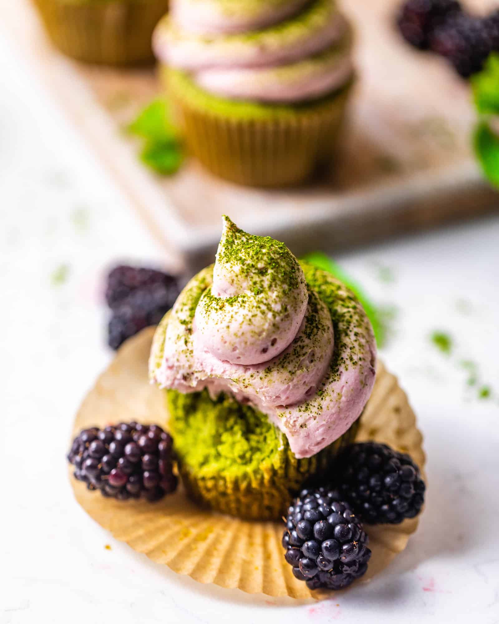 a matcha cupcake with a bite taken out of it.