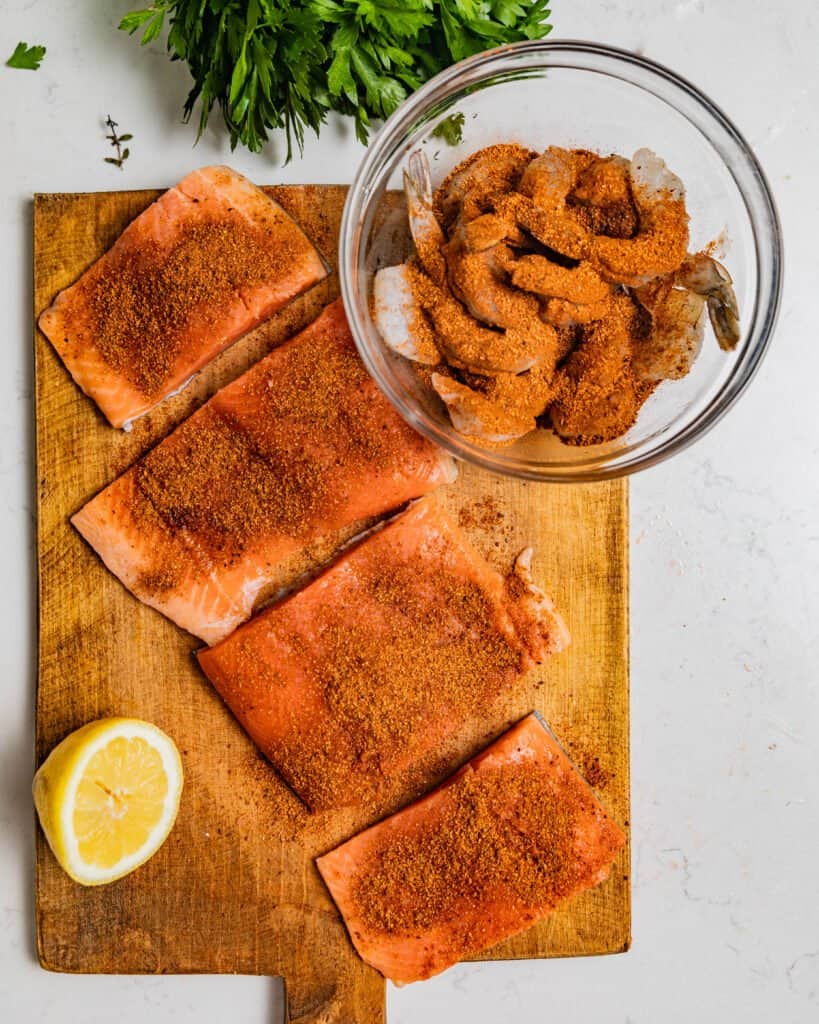 salmon and shrimp seasoned with cajun seasoning on a cutting board
