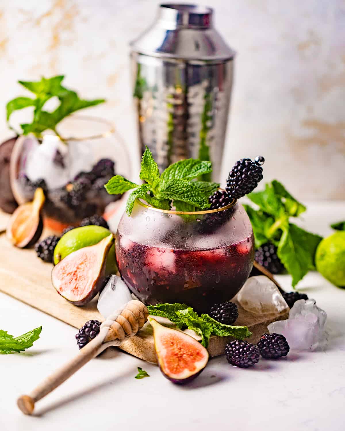 blackberry mojito on a serving board with a honey dipper and fresh mint leaves.