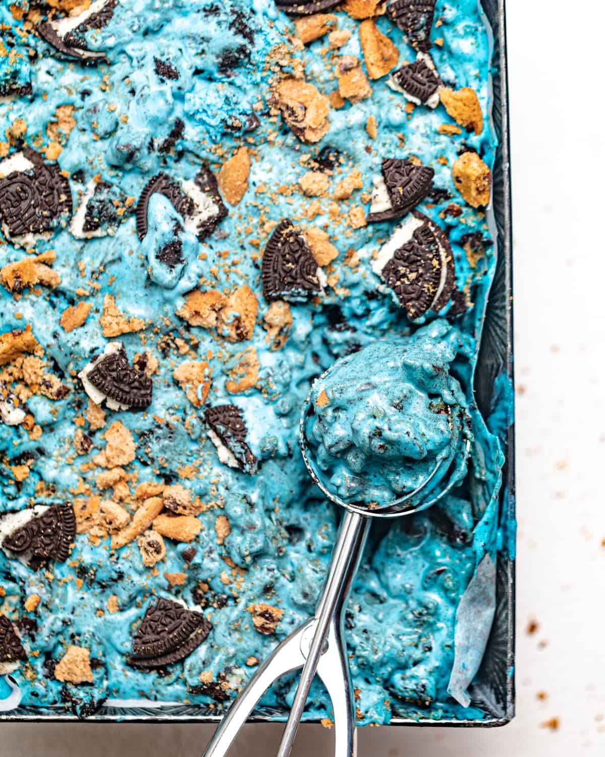 bright blue cookie monster ice cream in a pan with an ice cream scoop.