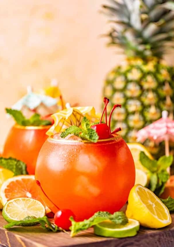 bahama mama cocktail on a brown tray with sliced lemons and limes