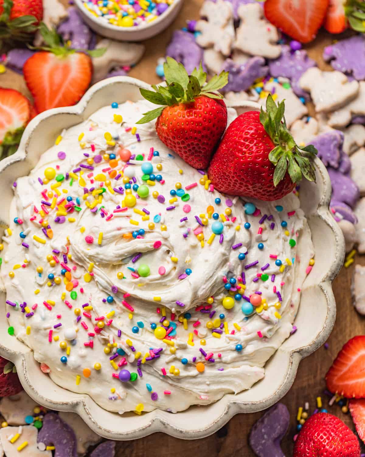 dunkaroo dip in a bowl garnished with rainbow sprinkles and strawberries.