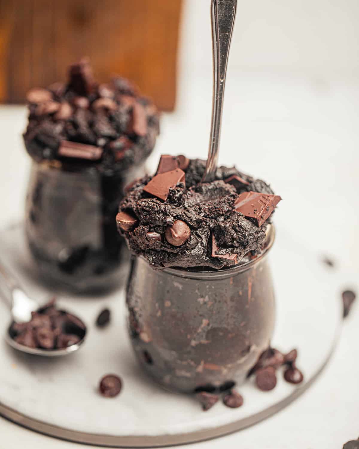 edible brownie batter in a small glass container with a spoon