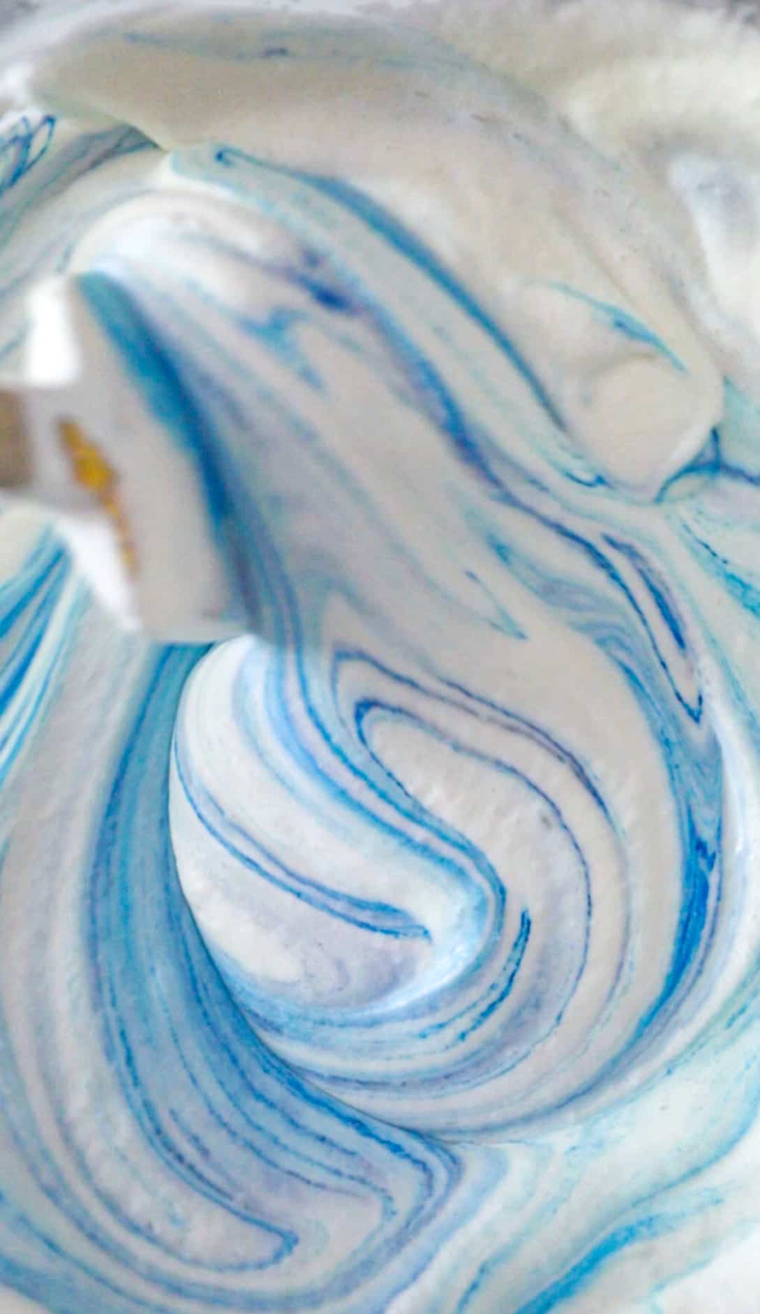 blue food coloring being added to the heavy whipping cream.
