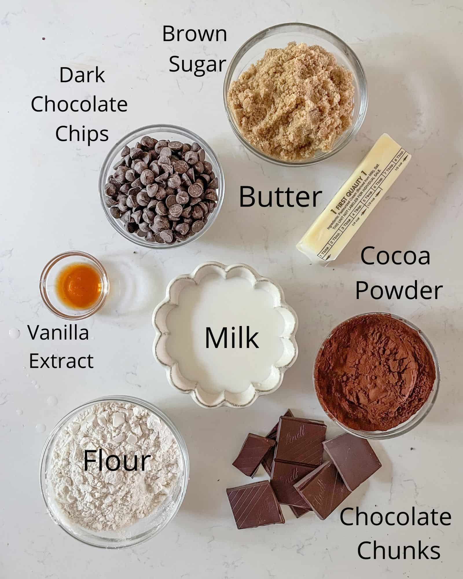 the ingredients to make edible brownie batter - brown sugar, butter, flour, cocoa powder, dark chocolate chips, vanilla extract, milk, and chocolate chunks.
