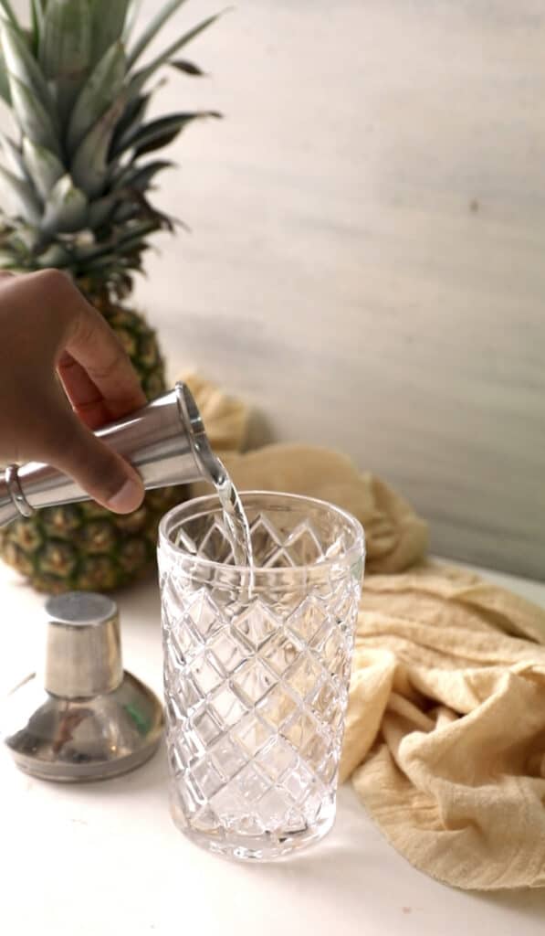 pouring coconut rum into a cocktail shaker.