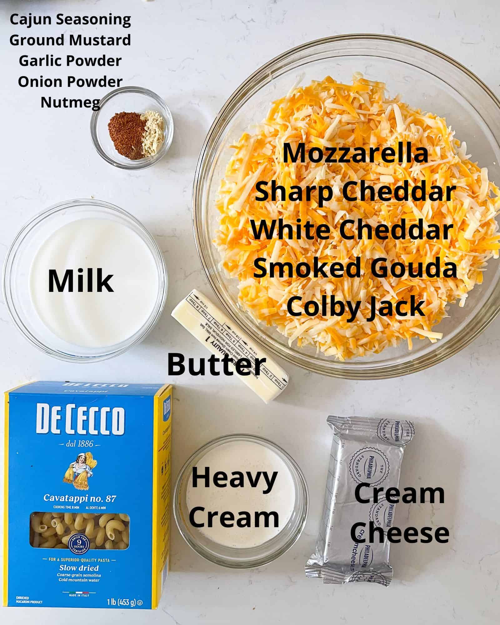 ingredients to make smoked mac and cheese - mozzarella, sharp cheddar cheese, white cheddar cheese, smoked gouda cheese, colby jack, milk, heavy cream, cream cheese, cajun seasoning, ground mustard, garlic powder, onion powder, salt and pepper, and elbow or cavatappi noodles.