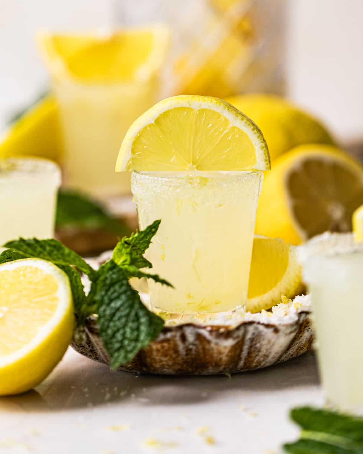 a single lemon grass shot in a bowl of sugar and lemon zest garnished with fresh mint leaves.