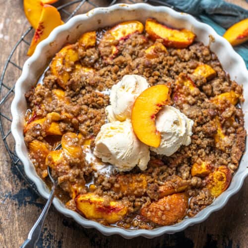 peach crumble in a pie pan with a spoon.