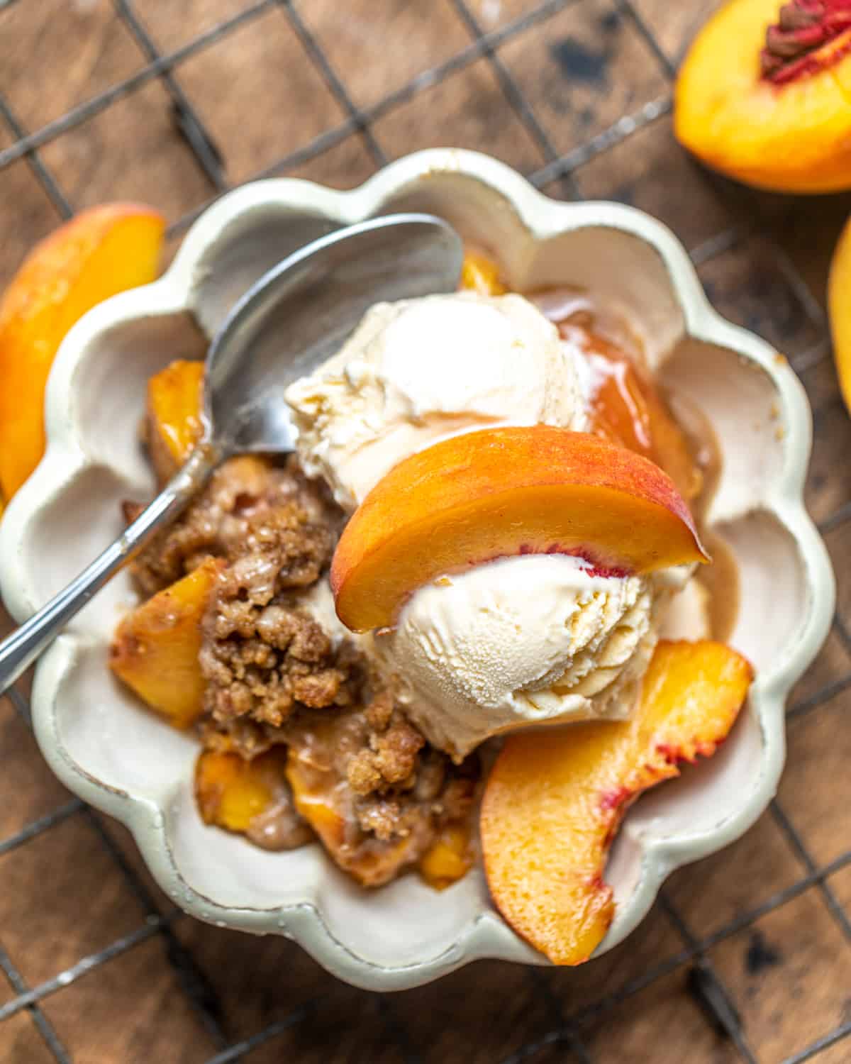 peach crumble in a bowl with ice cream on top.