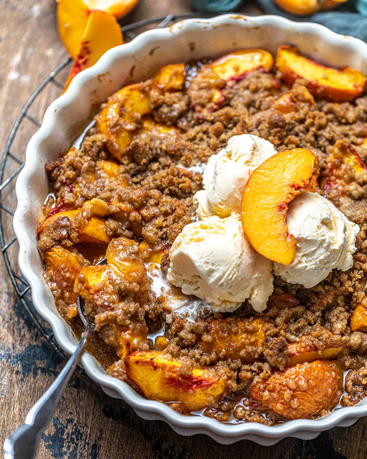 peach crumble in a pie pan with ice cream on top.