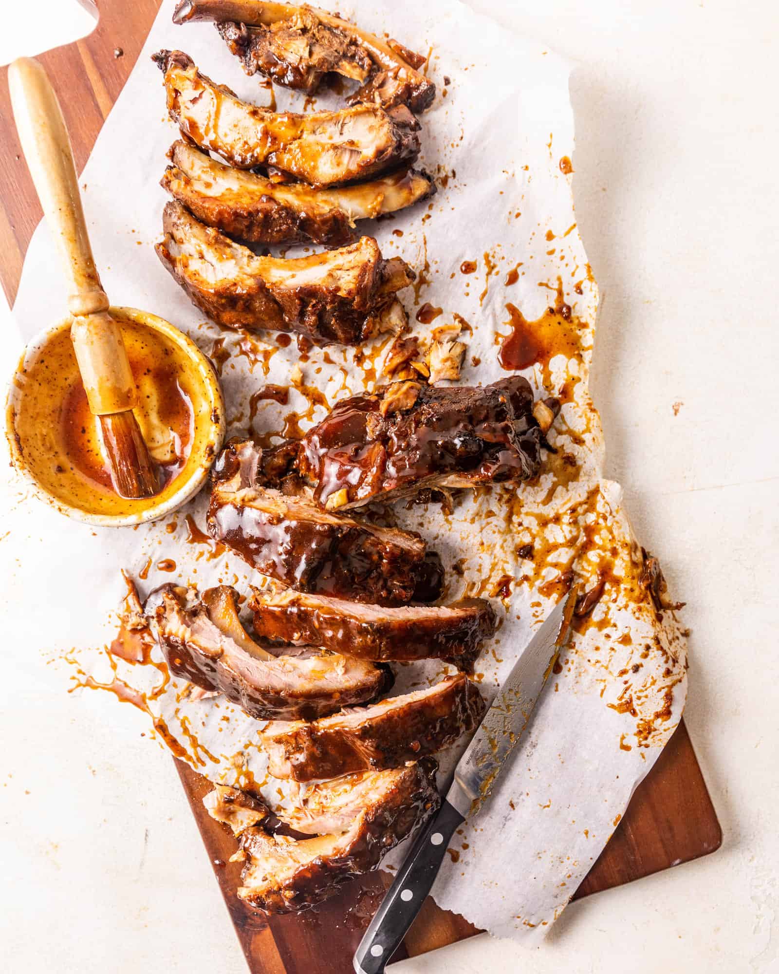 sliced baby back ribs on a tray covered in bbq sauce