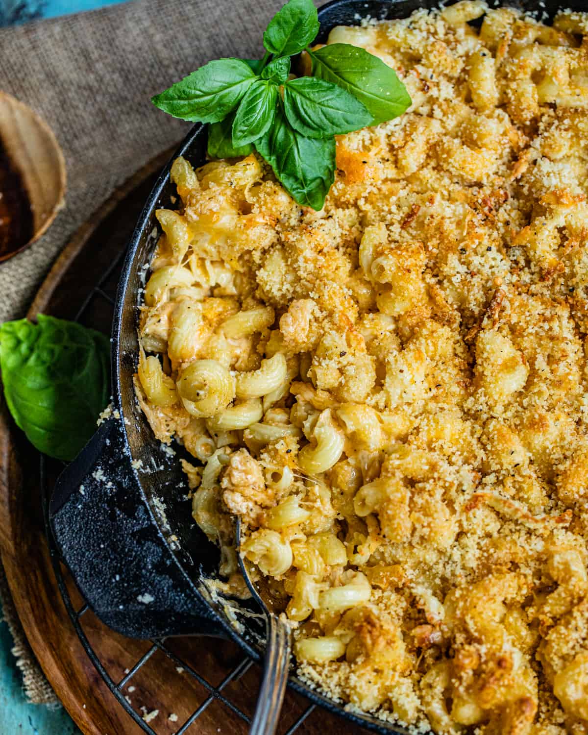 smoked macaroni and cheese in a cast iron skillet garnished with fresh herbs.