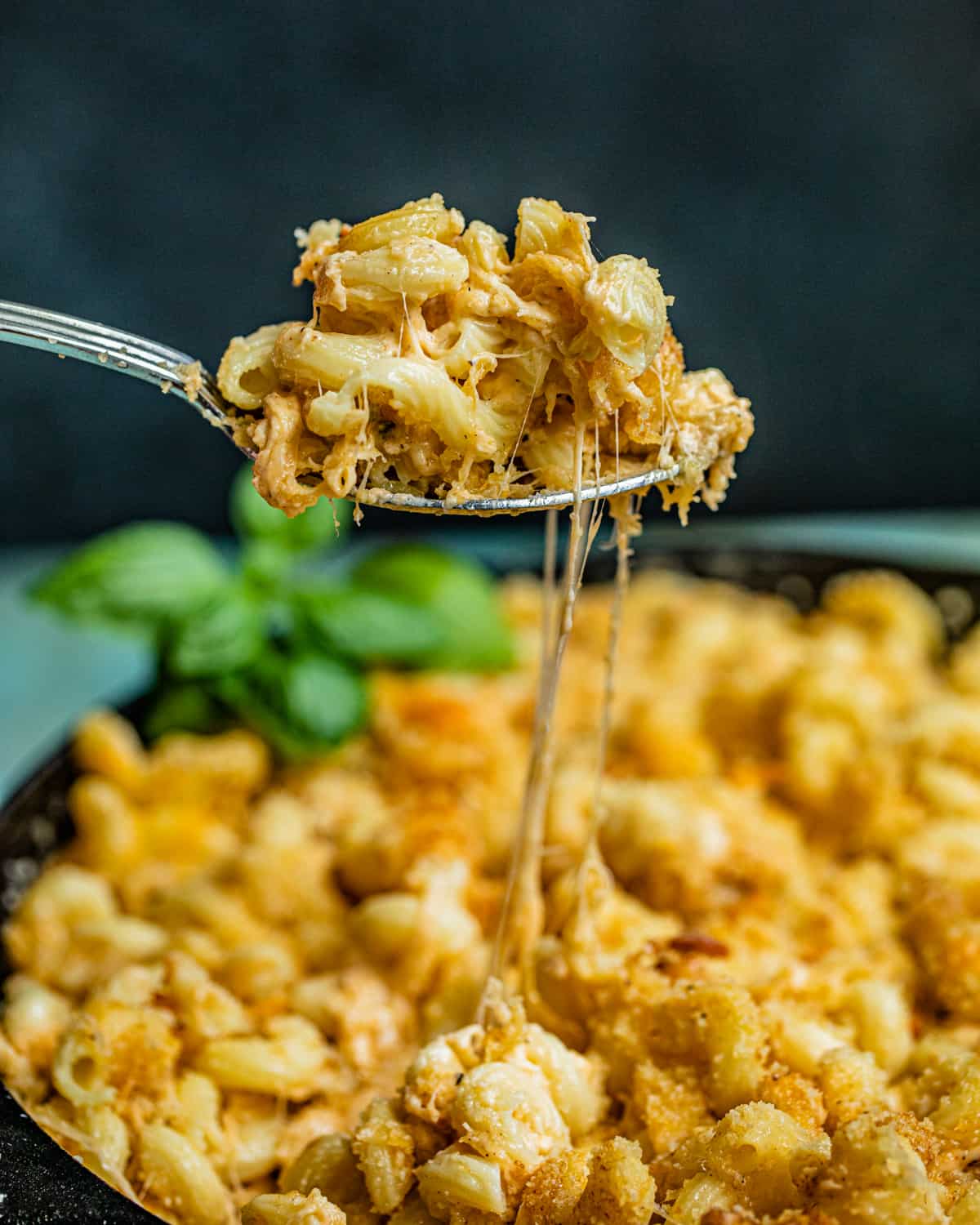 smoked mac and cheese being pulled out of a cast iron skillet on a spoon.